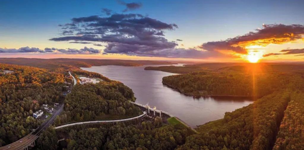 Une rivière avec un pont et une zone boisée.