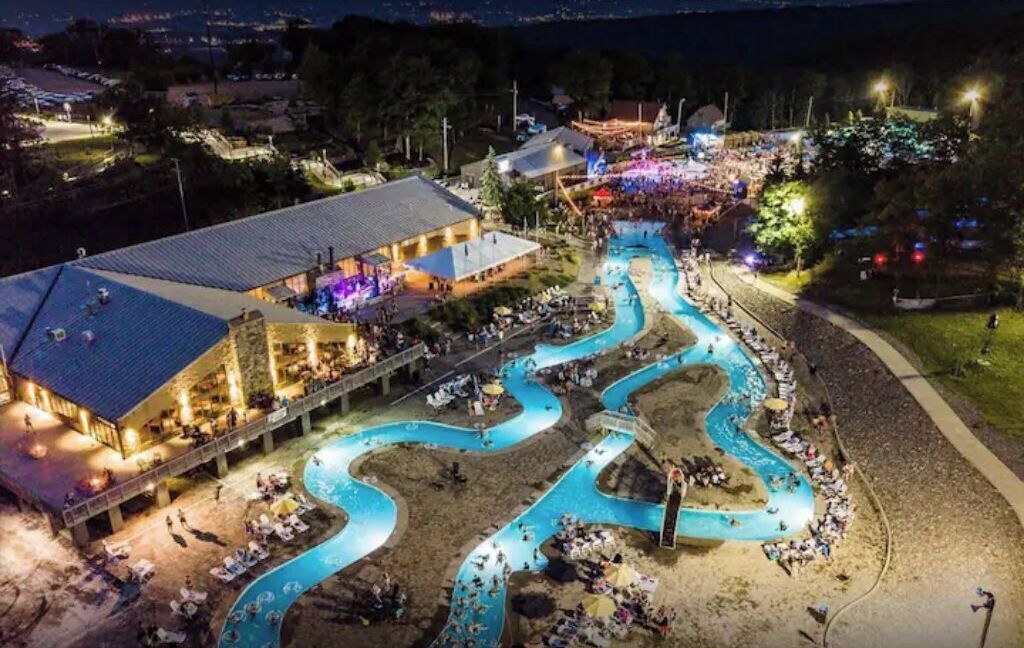 Ein Resort mit gewundenem Pool, Außenbereich zum Sitzen und einem Gebäude mit flachem Dach.