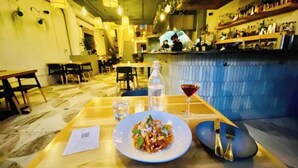 Een restaurantinterieur met een eettafel gedekt voor twee personen, met een bord eten, een glas water en een martini.