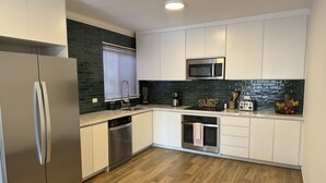 A modern kitchen with white cabinets, a stainless steel refrigerator, a microwave, and a dishwasher. - BEST DEAL IN HEART OF TAMARINDO. Block from the beach, walk to everything! (Tamarindo)