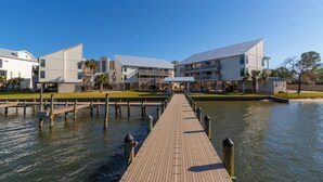 A waterfront hotel with a long wooden dock leading to the water, connected to multiple buildings with balconies. - SPRING/SUMMER DATES AVAILABLE (Orange Beach)
