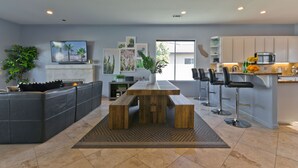 A modern kitchen with a wooden island, bar stools, and a dining table. - Great solar-powered house with pool/spa! (Palm Desert)