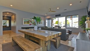 A spacious living area with a wooden dining table, benches, and a large window offering a view of the outdoors. - Great solar-powered house with pool/spa! (Palm Desert)