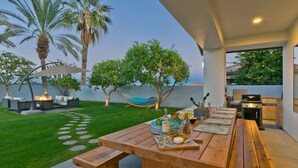 An outdoor dining area with a wooden table, a hammock, and a grill. - Great solar-powered house with pool/spa! (Palm Desert)