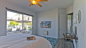 A bedroom with a bed, a desk, a ceiling fan, and a large window. - Great solar-powered house with pool/spa! (Palm Desert)