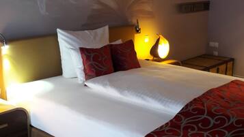 Ein Hotelzimmer mit Bett, Nachttisch, Lampe und Wandregal.