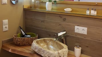 A bathroom with a stone sink, wooden vanity, and a mirror with a wooden frame.