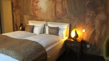 A double bed with a headboard, a bedside table with a lamp, and a mural on the wall.
