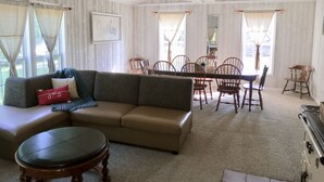 A spacious living room with a sofa, a dining table with chairs, a ceiling fan, and a fireplace. - The Homestead, at Nine Pines Farm - Hot Tub and Walking Trails (Nelsonville)