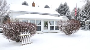 A white house with a snow-covered roof and a front porch. - The Homestead, at Nine Pines Farm - Hot Tub and Walking Trails (Nelsonville)