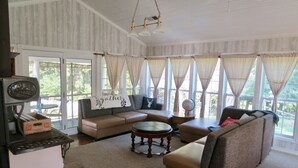 A cozy living room with a sectional sofa, a coffee table, and a vintage coffee maker. - The Homestead, at Nine Pines Farm - Hot Tub and Walking Trails (Nelsonville)