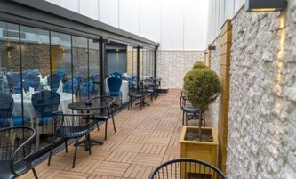 An outdoor patio area with tables and chairs, a stone wall, and a small potted plant.