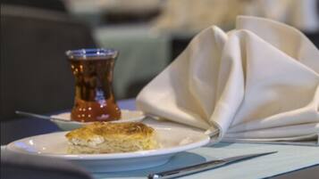 Un plato con un trozo de comida y una taza pequeña de salsa sobre una mesa.