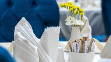 A table setting with folded napkins, a vase with yellow flowers, and a bowl with rolled-up towels.