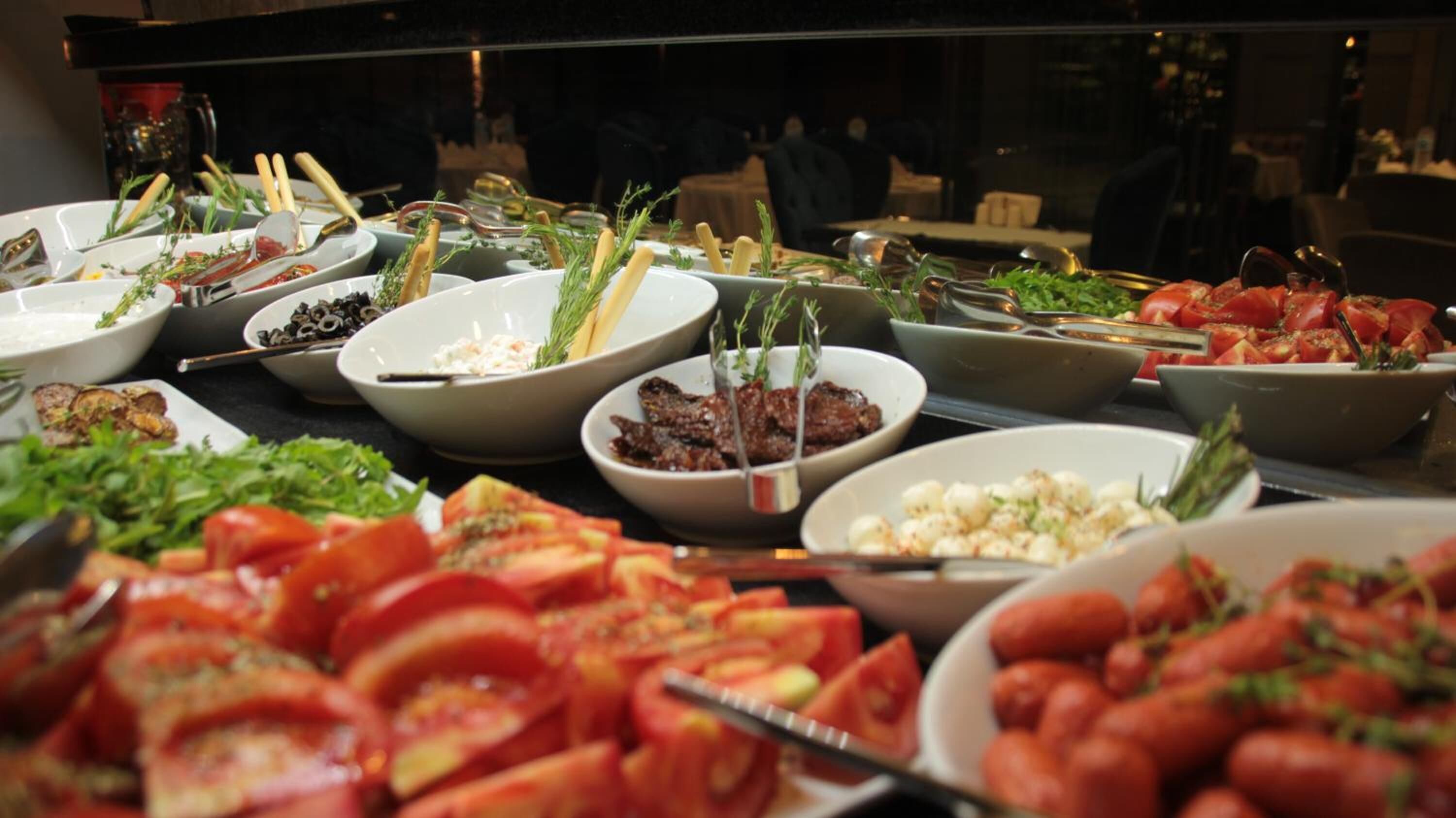 Un bufé con diversos platos, incluyendo ensaladas, carnes y verduras.