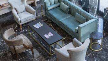 A modern living room with a teal sofa, two armchairs, a coffee table, and a bookshelf filled with books.