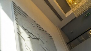 A modern interior with a geometric wall design, a wooden sculpture, and a marble floor. - Greymark Hotel (Izmir)