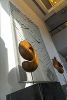 A modern interior with a geometric wall design, a wooden sculpture, and a marble floor.