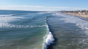 A beach with waves, a sandy shore, and a distant cityscape.