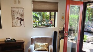 Une pièce avec une grande fenêtre, une chaise, un lit et une petite table.