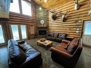 A log cabin interior with a stone fireplace, leather furniture, and mounted deer heads. - Unbeatable view; hot tub; theater; 9’ spiral slide; arcade games; coupons&treats (Garden City)