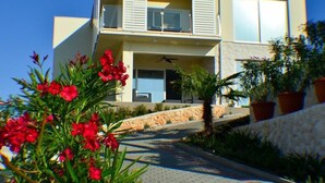 Un bâtiment moderne à deux étages, doté d’un balcon, d’un chemin en pierre et de plantes en pot.