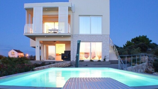 Une maison moderne à deux étages, dotée d’une piscine et d’une terrasse.