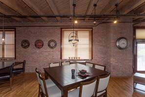 A dining area with a brick wall, wooden ceiling, and a large round table with chairs. - In The Heart of Lower Downton Denver in a beautiful historic building. Unit 303B (Denver)