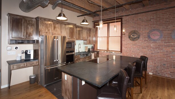 A modern kitchen with stainless steel appliances, wooden cabinets, and a large island with bar stools.