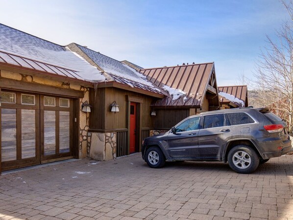 Ein Haus mit Garage, einem abgestellten Geländewagen und einem mit Schnee bedeckten Dach.