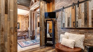 A rustic interior with exposed wooden beams, a leather ottoman, and a mounted television. - Large, Luxe, walk2town, 2 min DV & PC bases. Theater, game room, steam room (Park City)