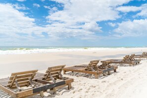 A beach with wooden lounge chairs arranged in rows.