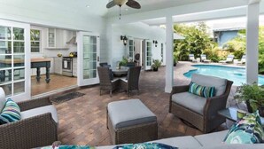 Eine Außenpatio mit Korbmöbeln, einem Deckenventilator und einem Pool.