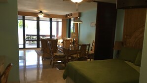 A room with a bed, a dining table with chairs, a ceiling fan, and a view of the outdoors.