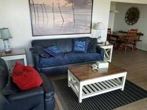 A living room with a blue sofa, a wooden coffee table, and a red cushion.