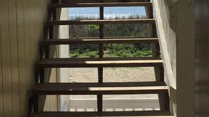 A wooden staircase with a white railing leading to a balcony.