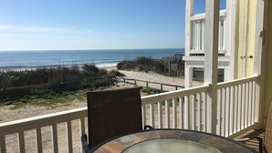 A balcony with a view of the beach and ocean.