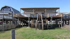 Un bâtiment situé en bord de mer, doté d’une terrasse en bois et d’un escalier menant à un balcon.