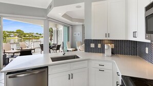 A modern kitchen with white cabinetry, a black and white backsplash, and a large island with a sink. - LAKEFRONT! UPDATED IN PAST 3 months ! Fish out back from porch! Minutes to beach (Miramar Beach)