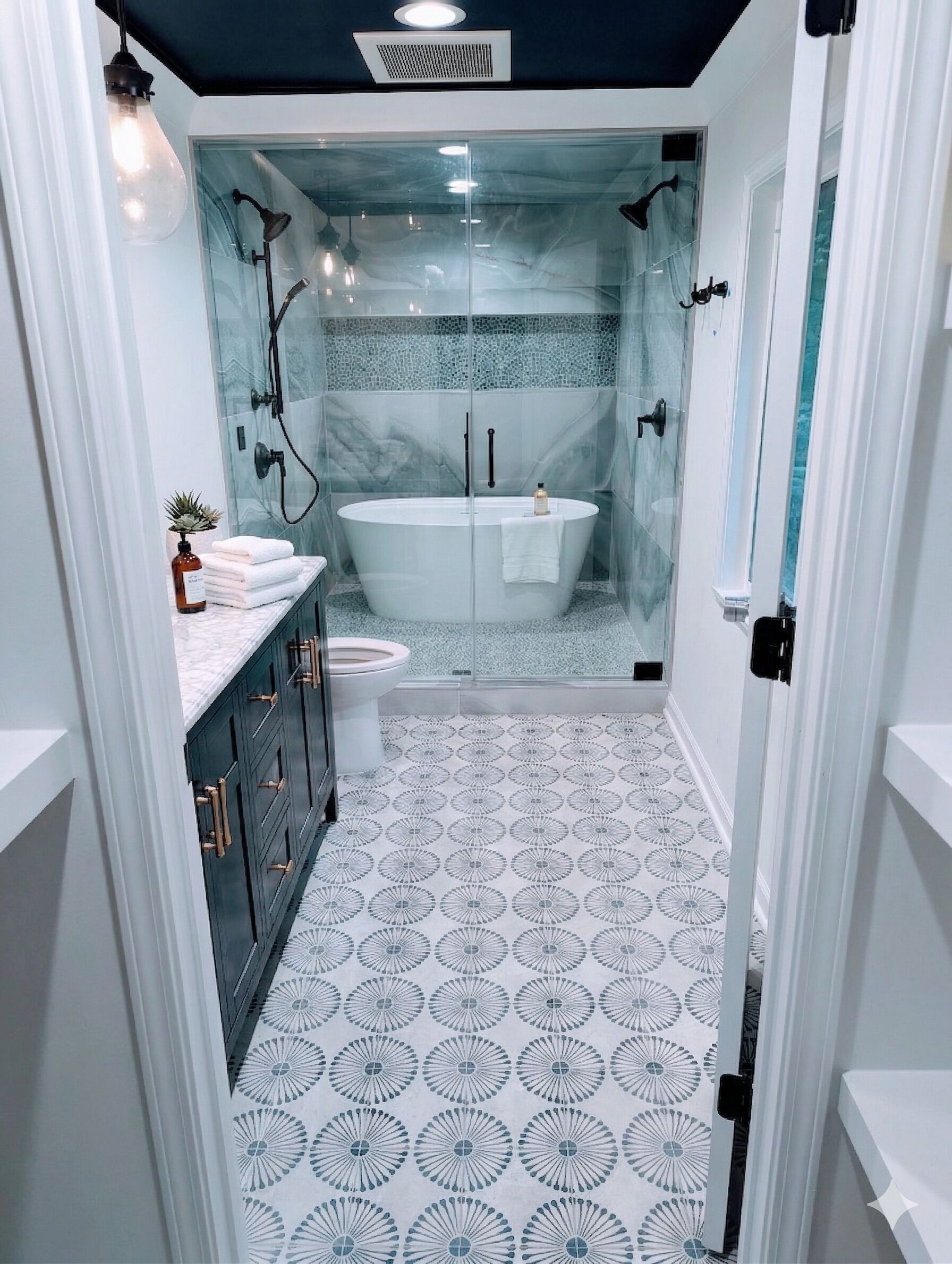 A modern bathroom with a freestanding bathtub, a glass shower enclosure, and patterned floor tiles.