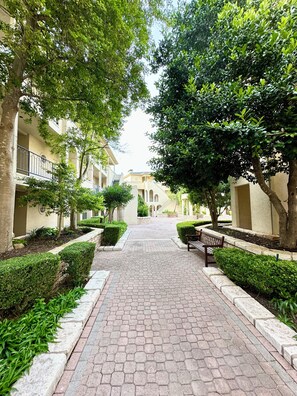 Stroll through the serene courtyard, lined with neatly trimmed hedges and mature trees, to the central building with a classical architectural style.