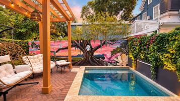 A pool area with a mural, wicker chairs, and a pergola.