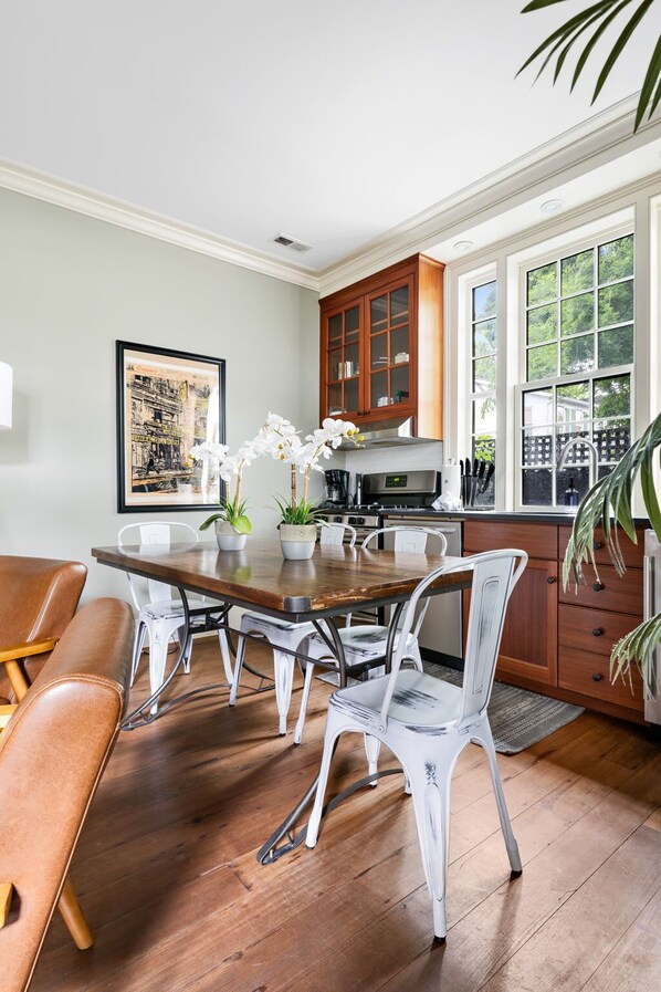 Una cocina moderna con una mesa de comedor de madera, sillas blancas y un ventanal amplio.