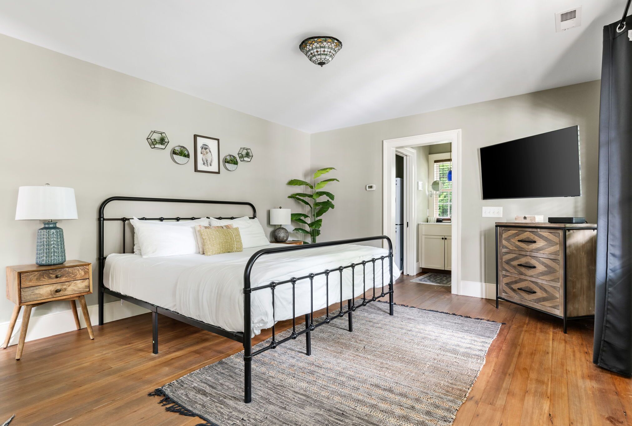 A bedroom with a bed, bedside table, lamp, and a TV.