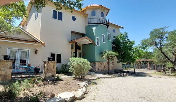 A two-story house with a unique green tower section, a stone entrance, and a visible swimming pool. -  Secluded Lakeview, Hot Tub, 3 acres, Deer, Spacious Yard, The Preserve Venue (Canyon Lake)