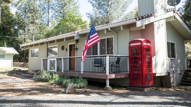 A house with a porch, an American flag, and a red telephone booth.