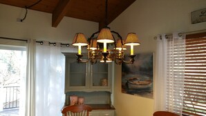 A dining area with a chandelier, a window with blinds, and a painting on the wall.