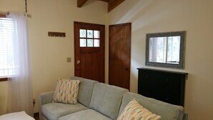 A living room with a sofa, two doors, a window, and a wall-mounted cabinet.