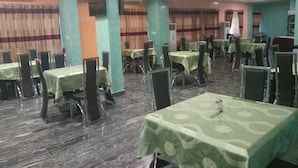 Un espace repas comprenant plusieurs tables et chaises, des unités de climatisation et un écran de télévision.
