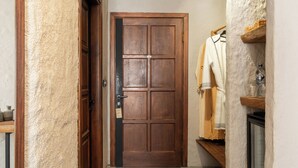 A wooden door with a keyhole and a small sign, a wooden shelf with a basket, and a hanging garment. - GAIA Alacati (Cesme)
